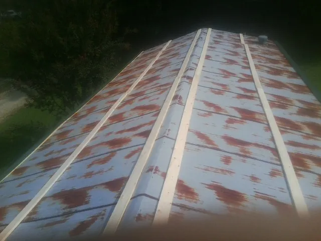 Rusted metal roof panels with new wood purlins before replacement — Storm Damage Roof Repair in South Sterling by Roofing Brothers