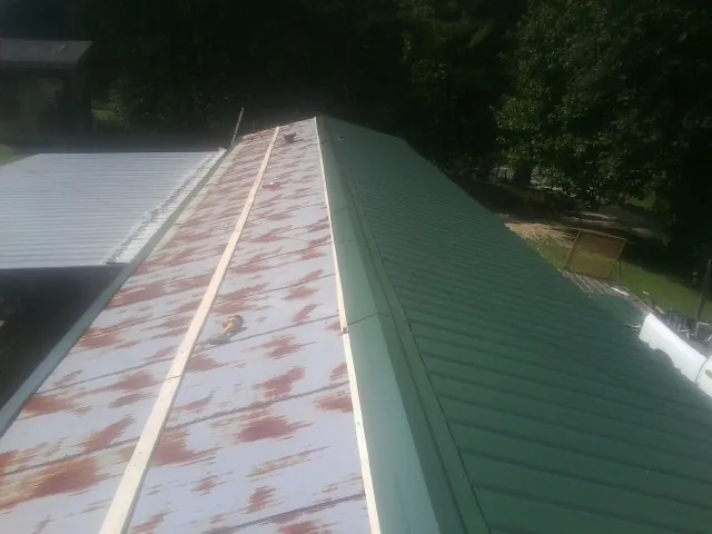 Old rusted panels beside newly installed green metal roofing — Wind Damage Roof Repair by Roofing Brothers in South Sterling
