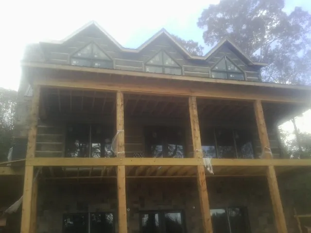 Dormers and porch framing on a large log home under construction — Roof Coating work by our crew in South Sterling
