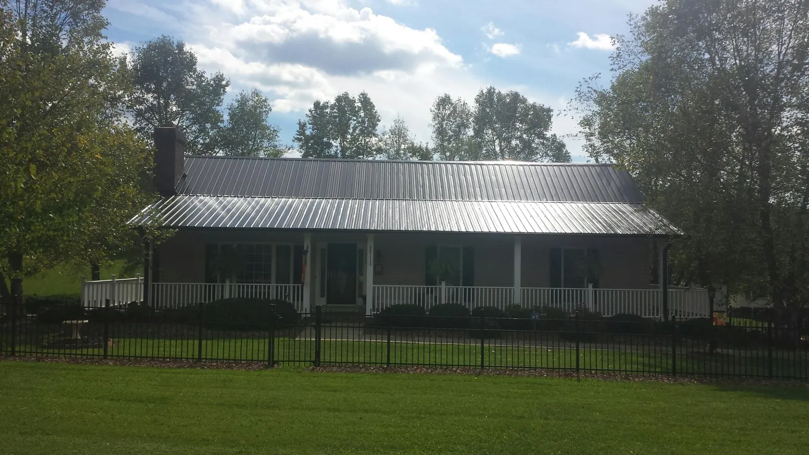 Gray metal roof on a brick ranch with a full width front porch — Gutter Guard Installation work by our crew in South Sterling