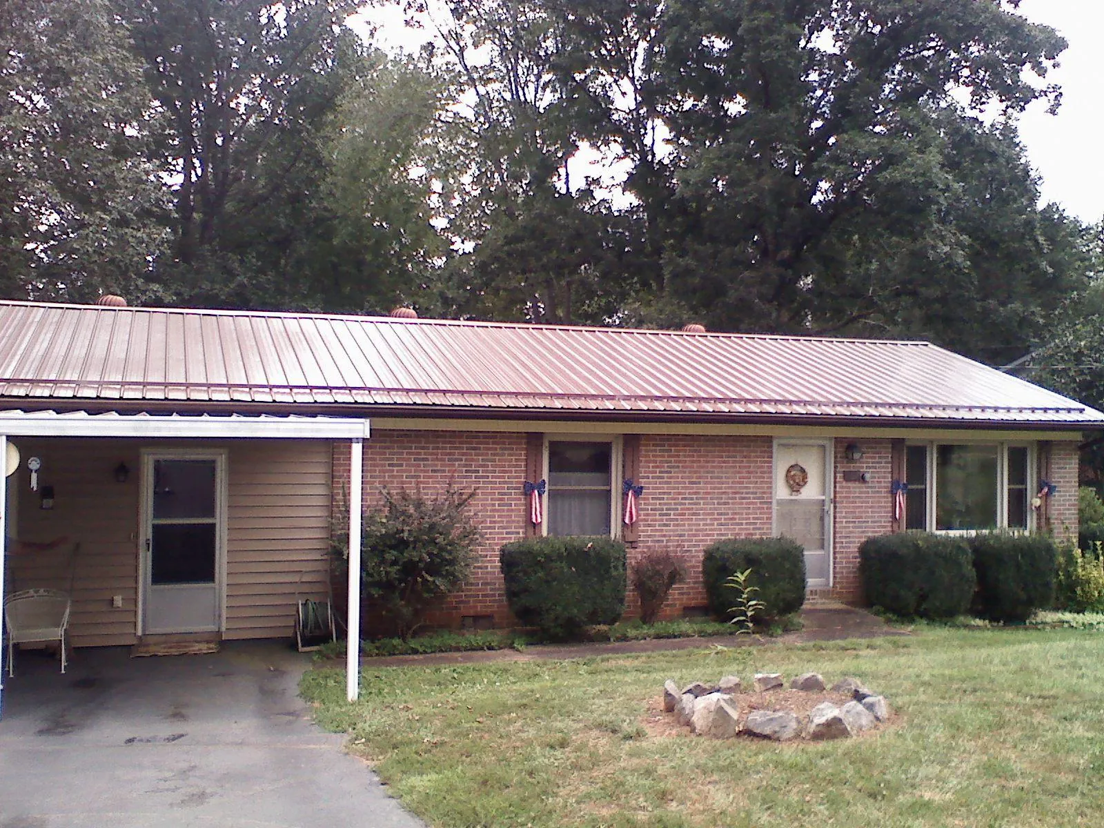 Bronze metal roof and carport on a brick ranch home — Roof Repair work by our crew in South Sterling