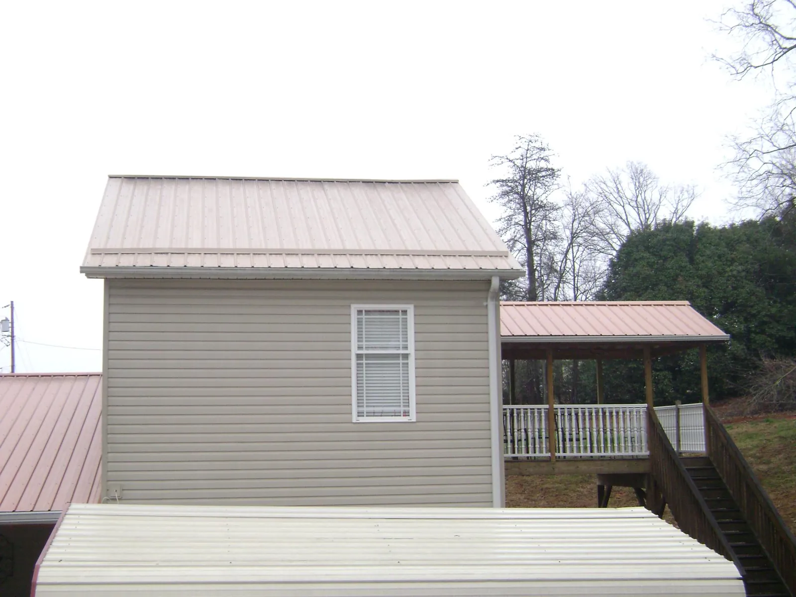 Tan metal roofs on a two story addition and attached porch, from a Roof Replacement job in South Sterling